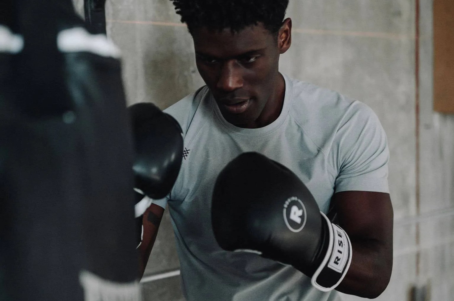 a man boxing at a bag in a gray t shirt