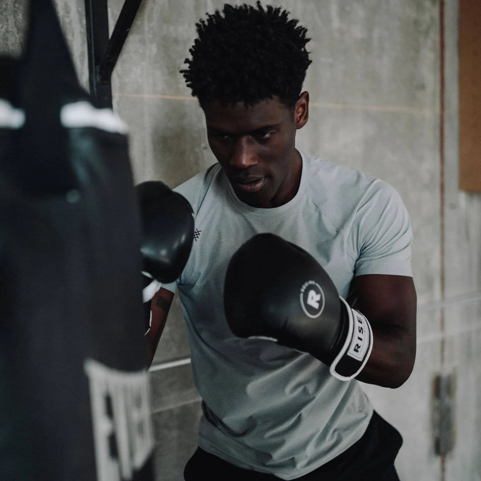 a man boxing at a bag in a gray t shirt
