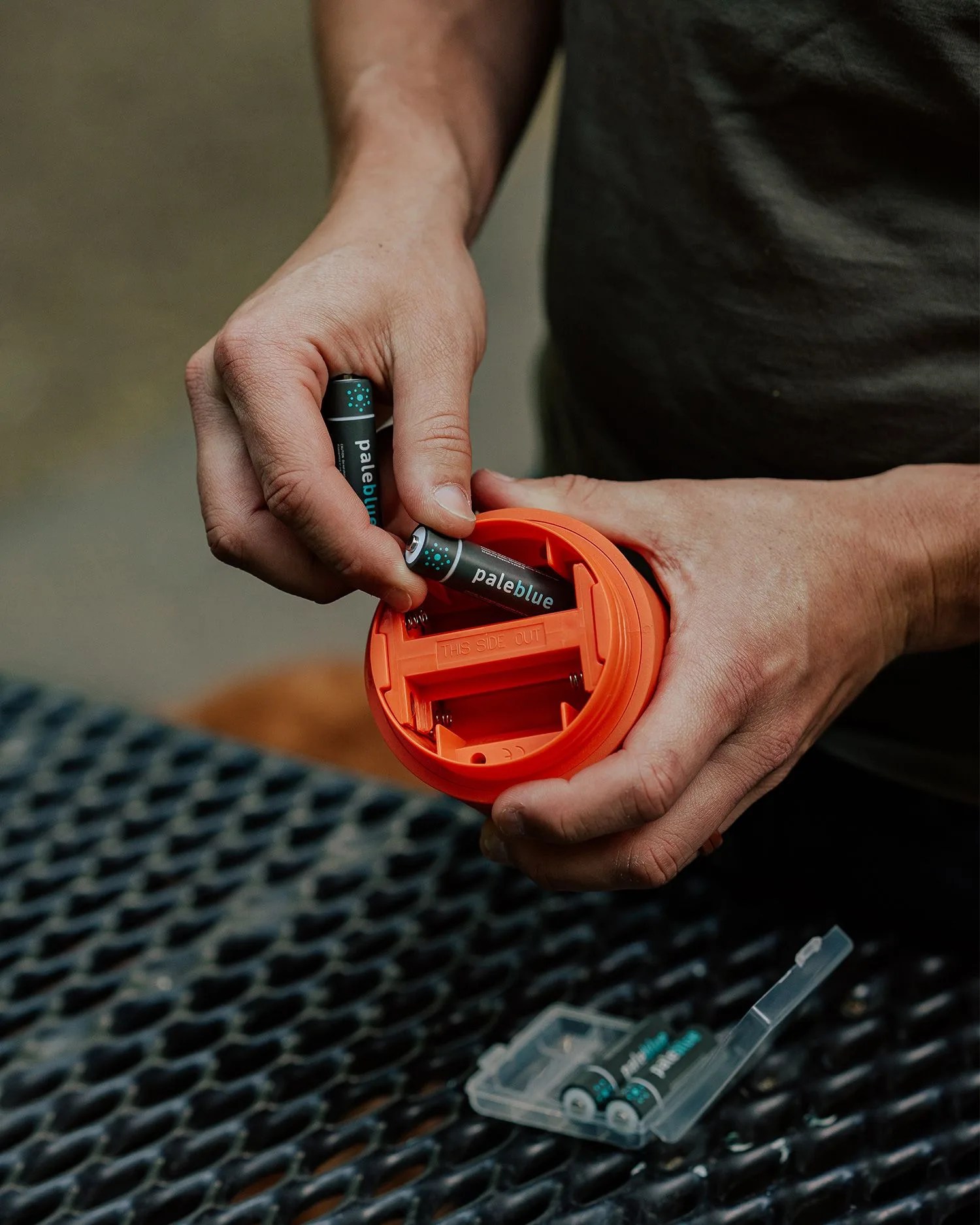 man putting pale blue batteries into device