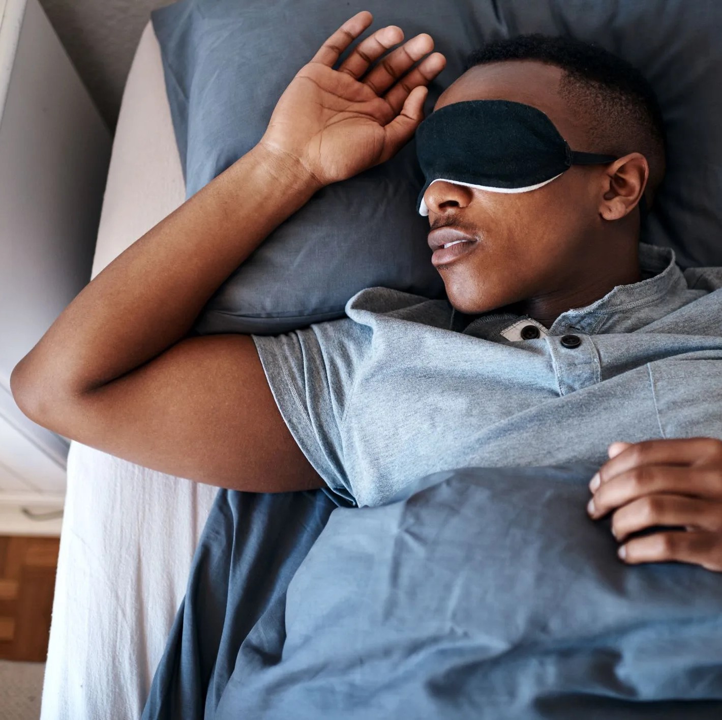 man sleeping in bed wearing eye mask