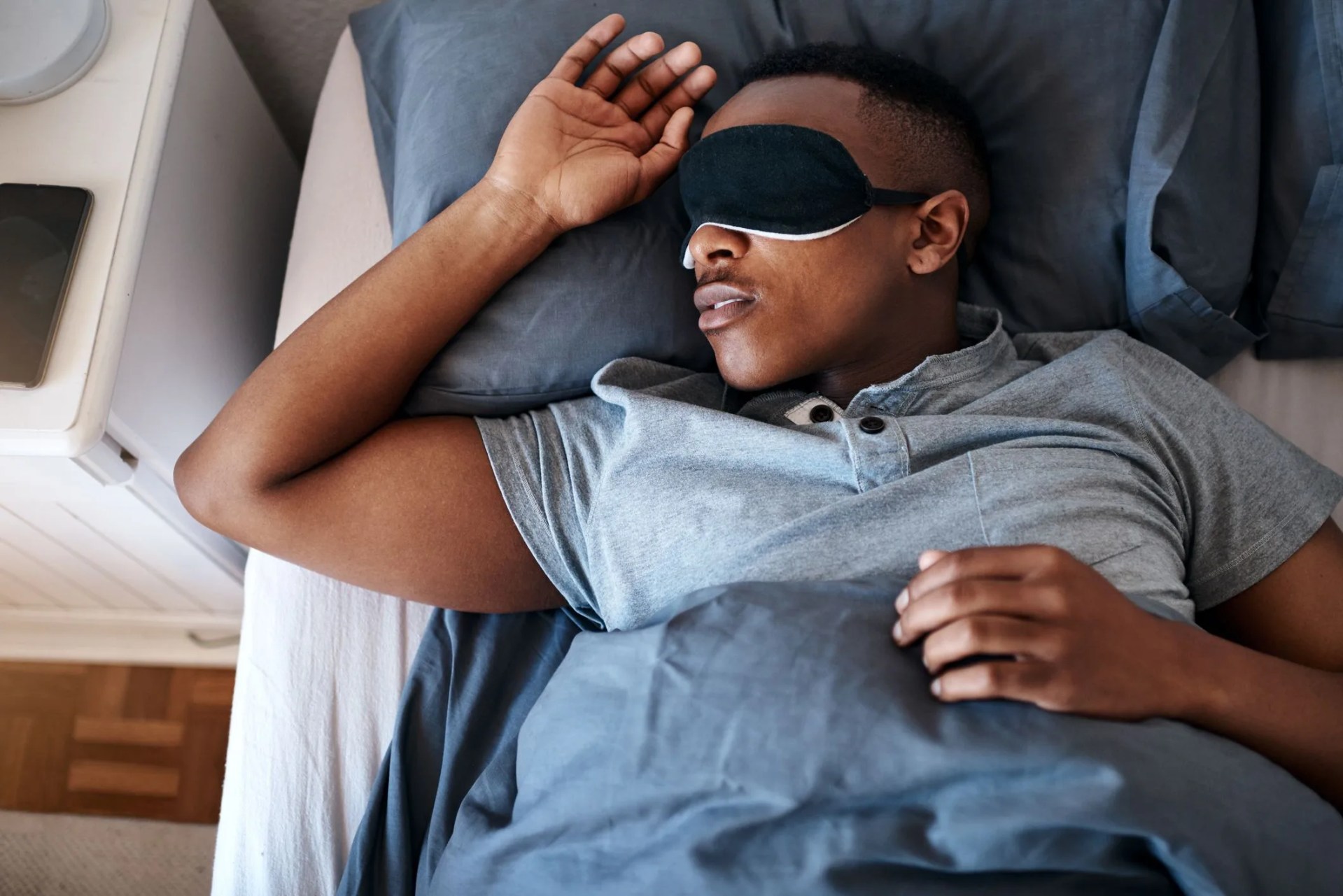 man sleeping in bed wearing eye mask
