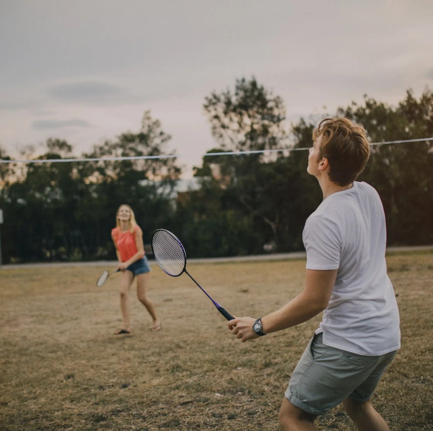 young couple playing badminton in the park