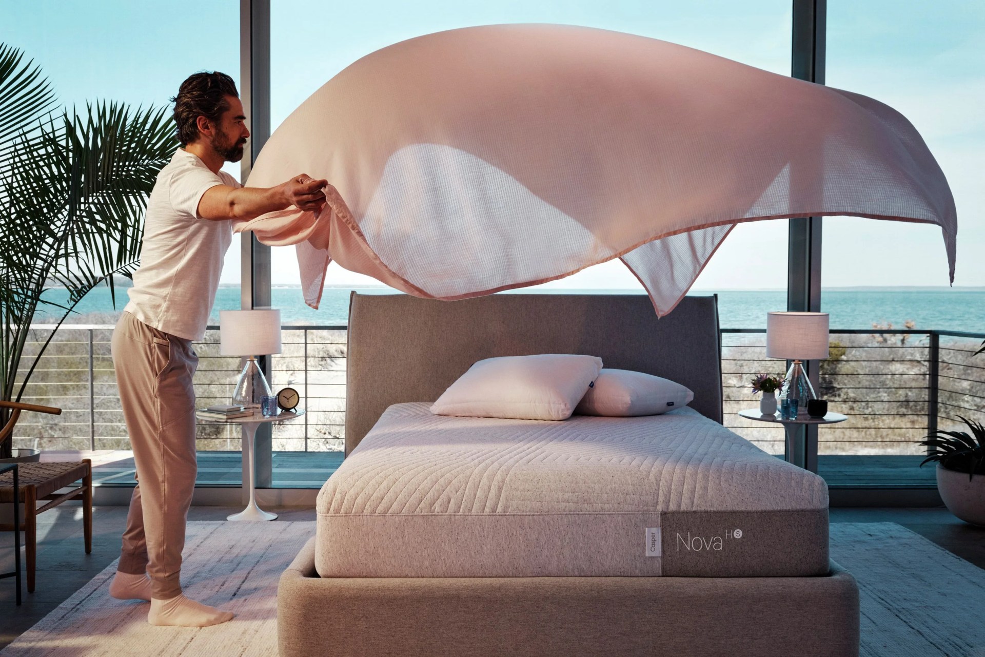 man putting sheets onto bed
