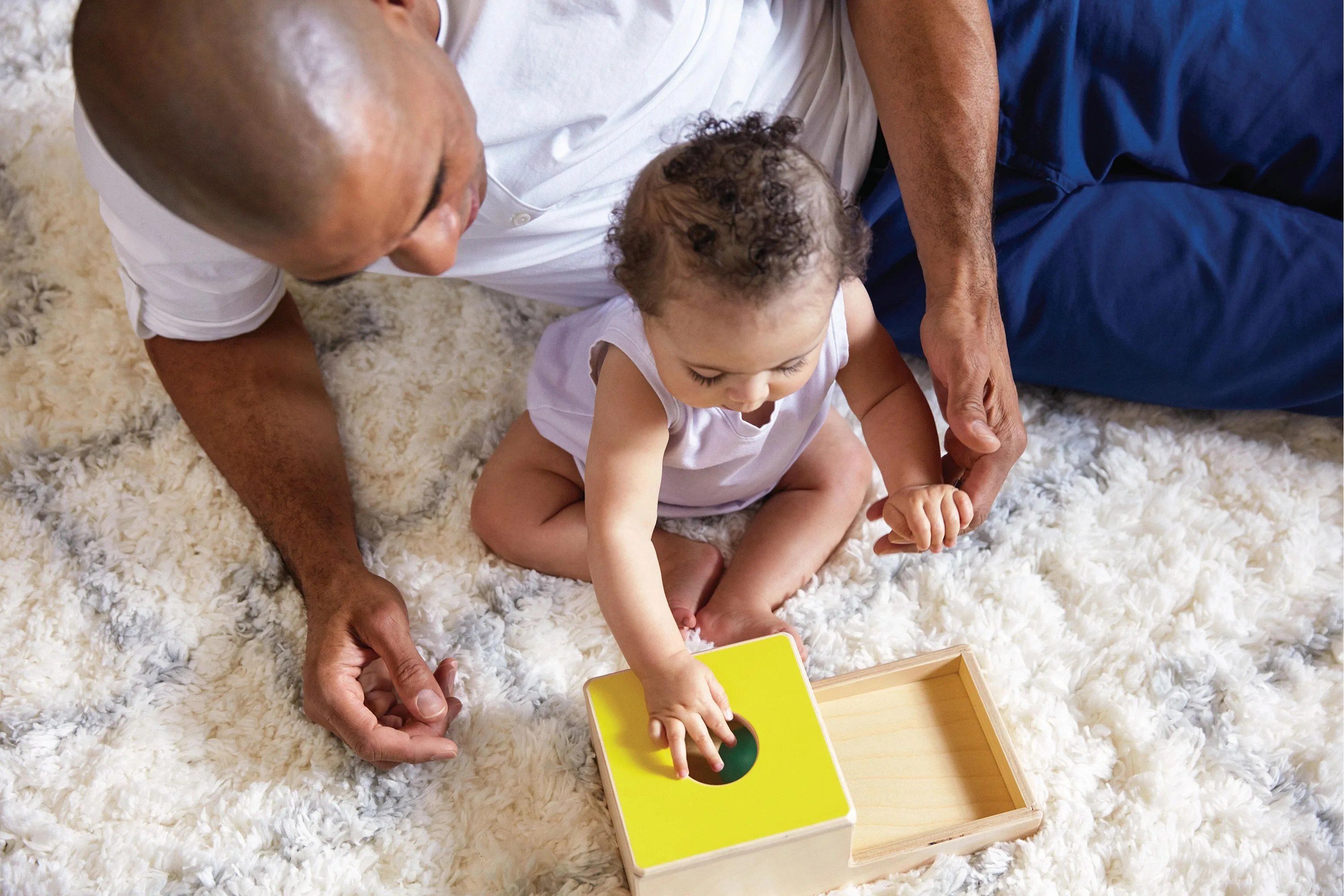dad supervising kid playing with lovevery toy