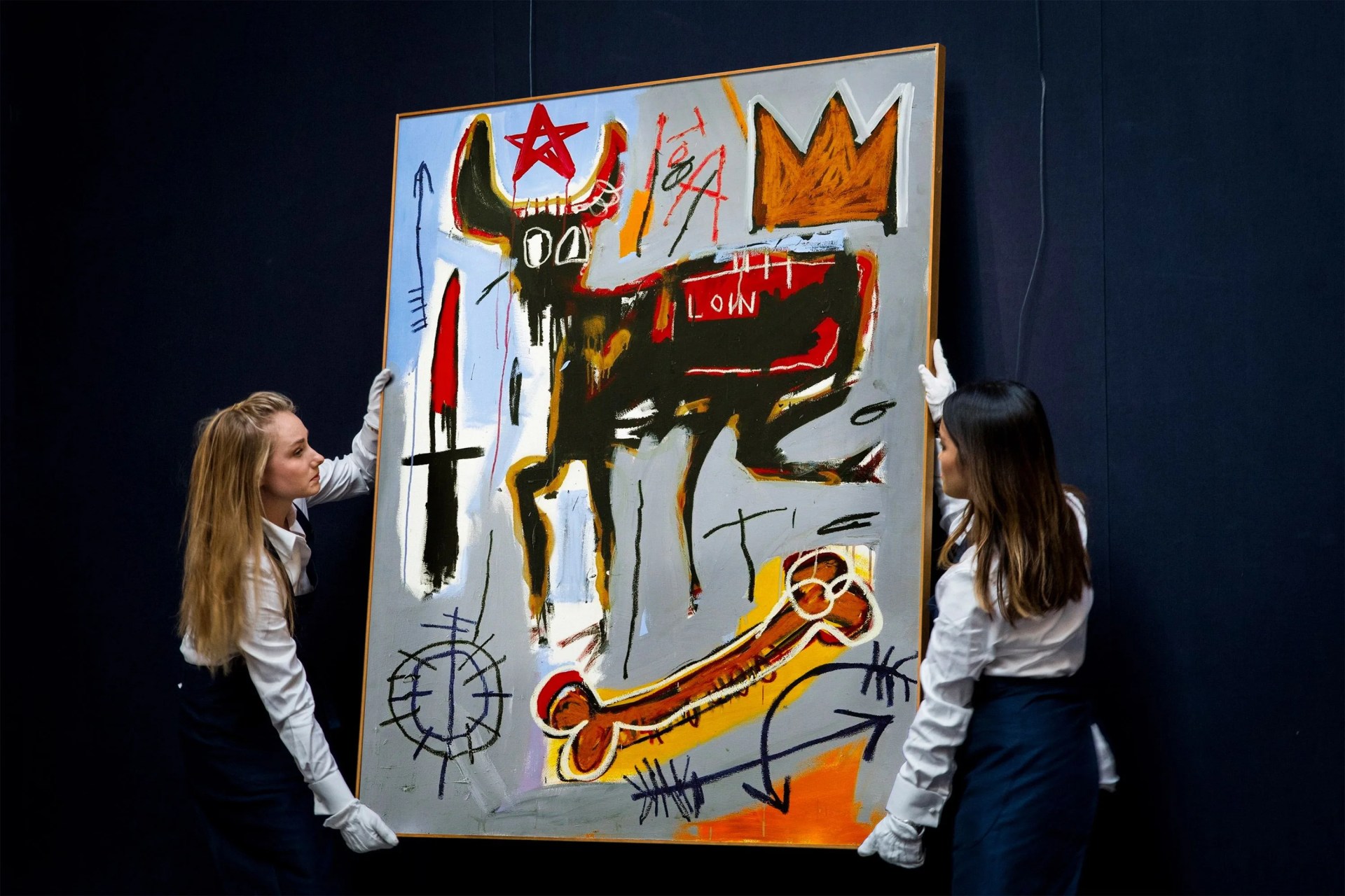 two women holding up a contemporary painting