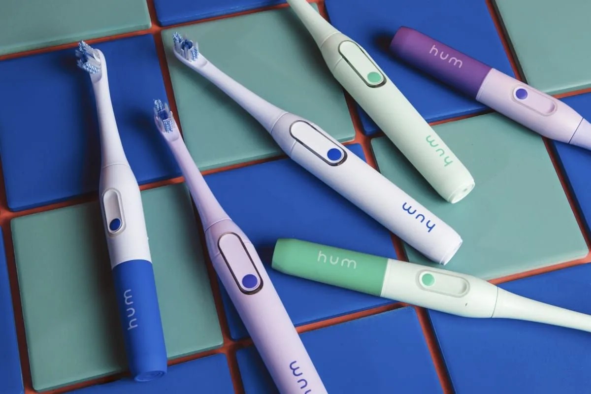 six electric toothbrushes against blue and green bathroom tiles