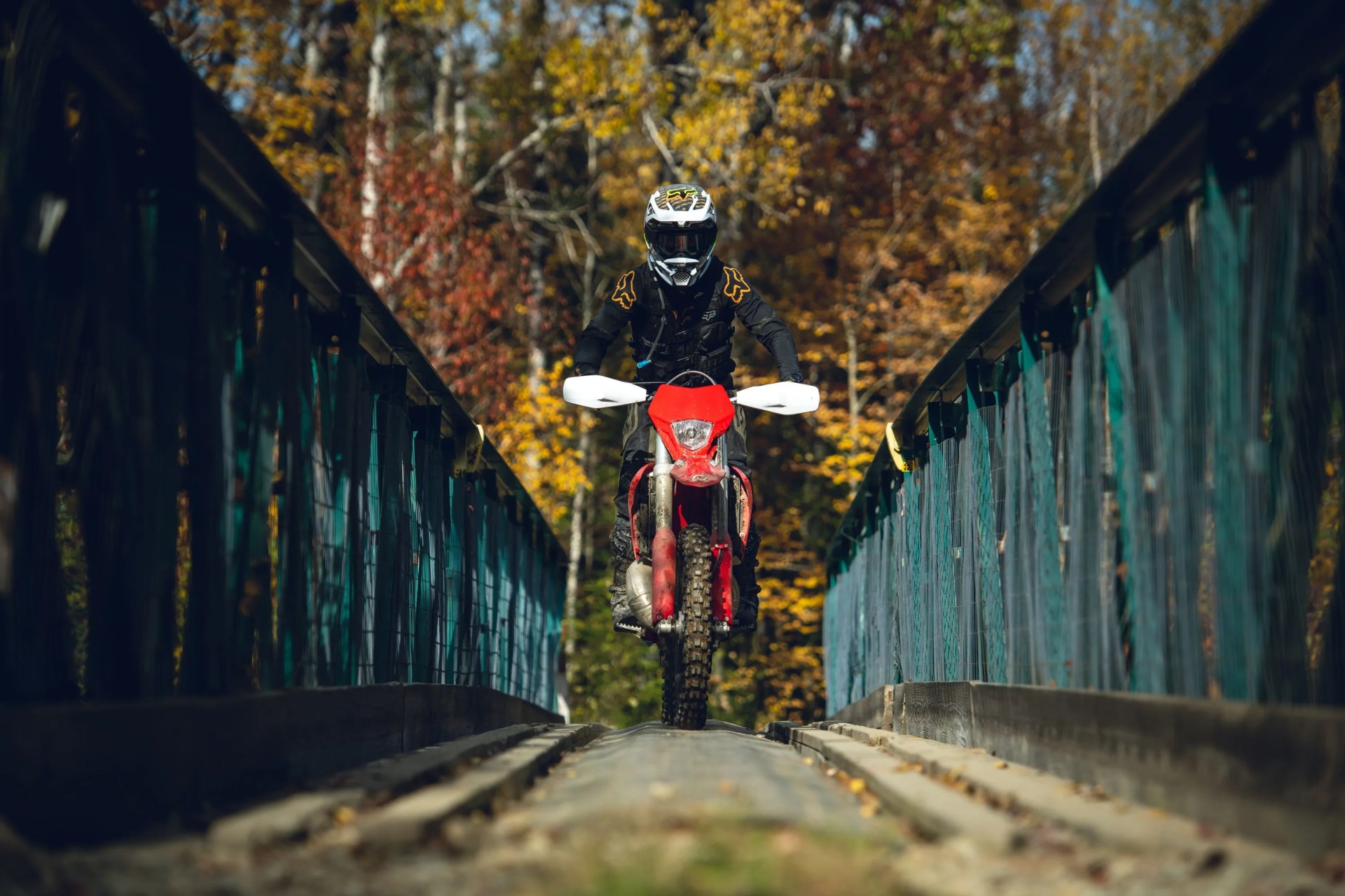 person riding across bridge wearing fox racing gear