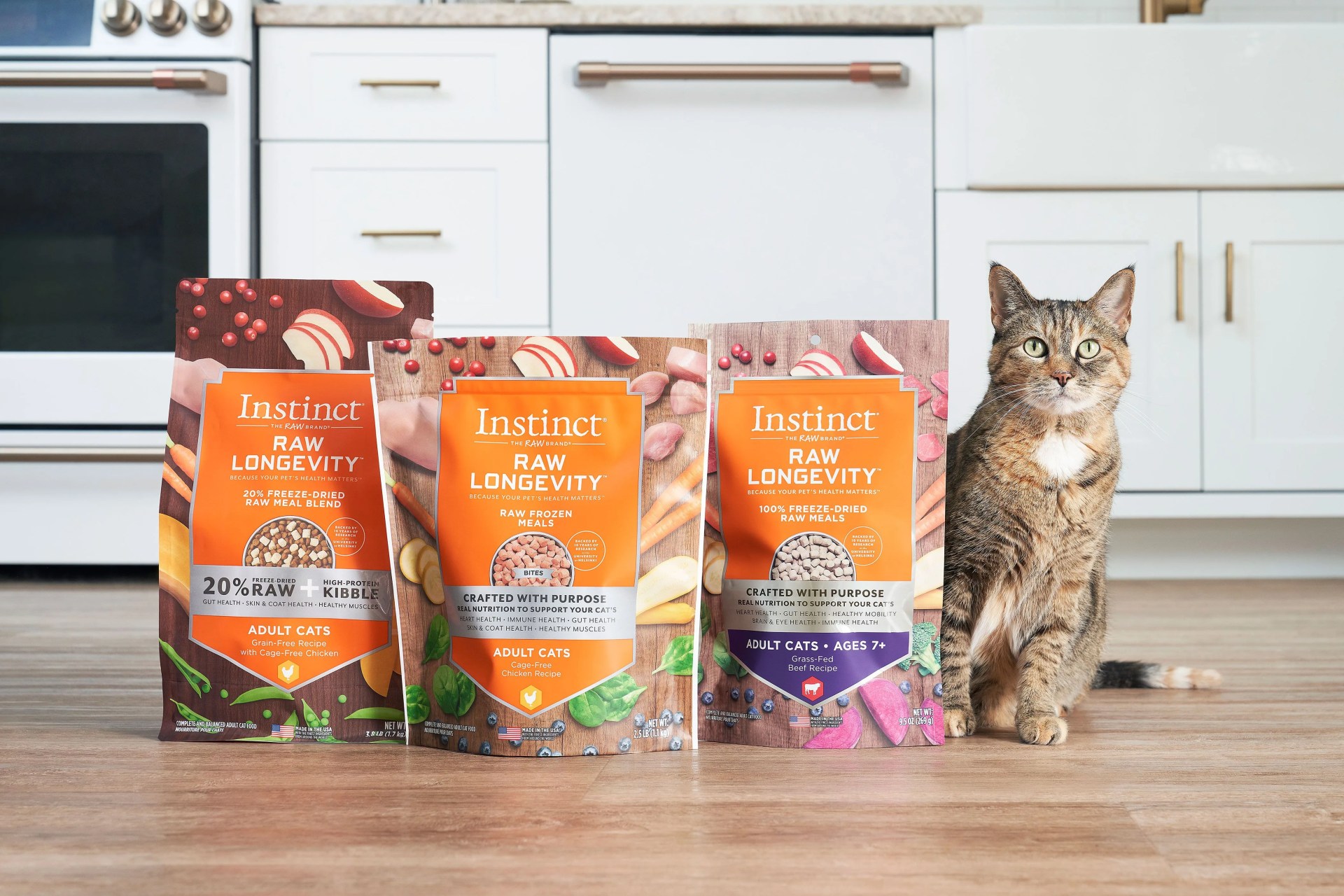 cat sitting next to three flavors of instinct kibble bags