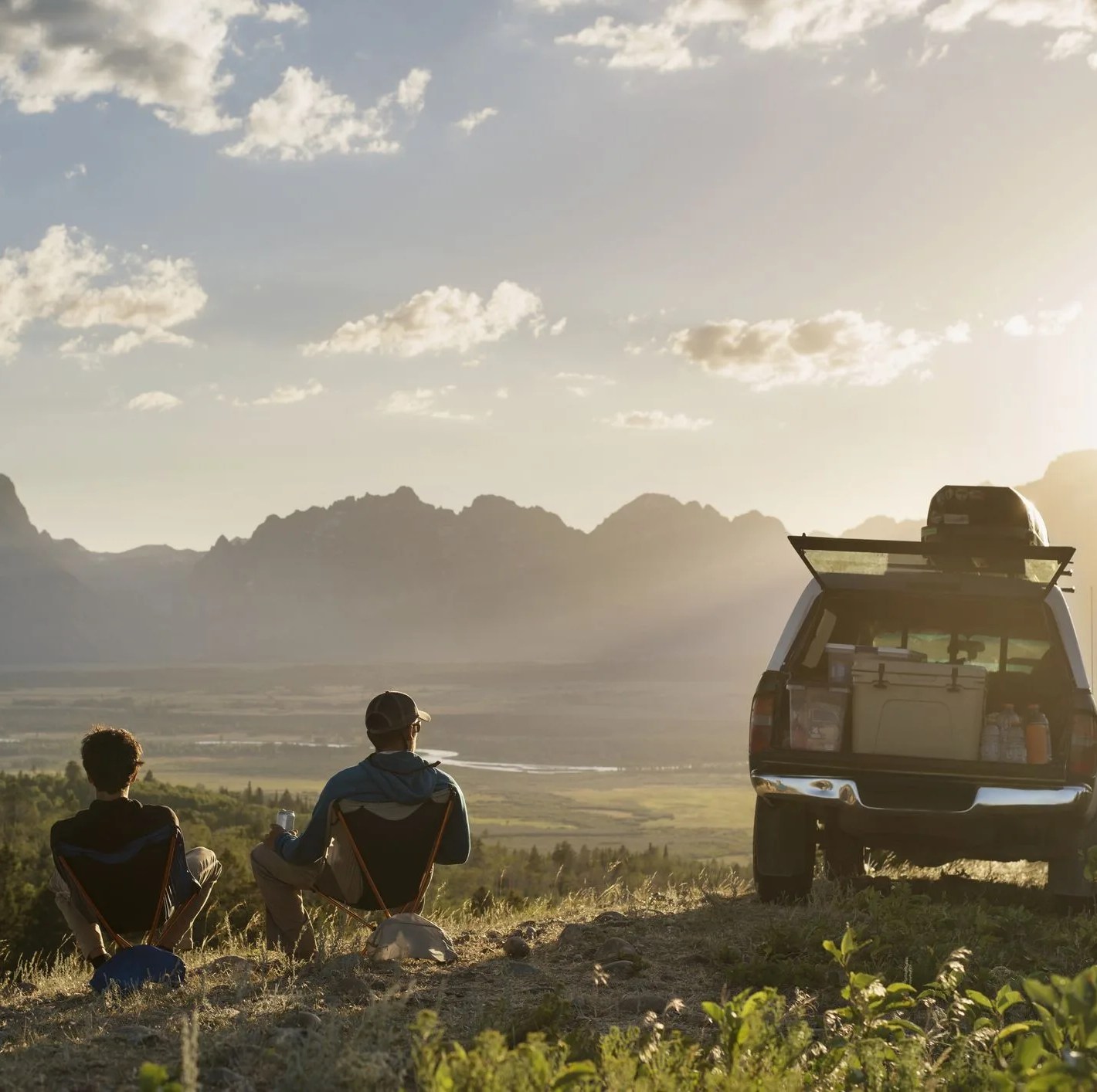 Rear view of male hikers relaxing on reclining chair in field