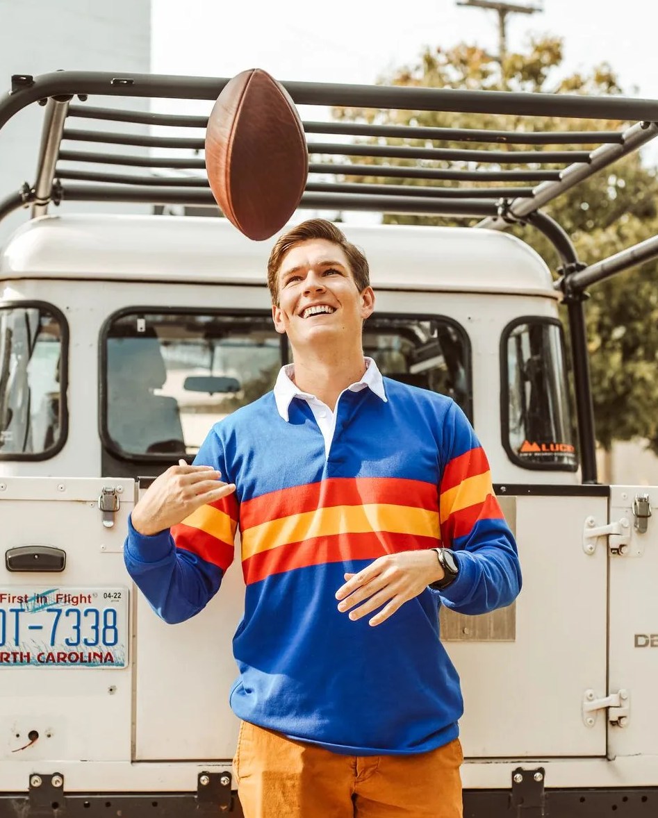 man wearing huckberry ulysses rugby shirt while tossing a football in the air