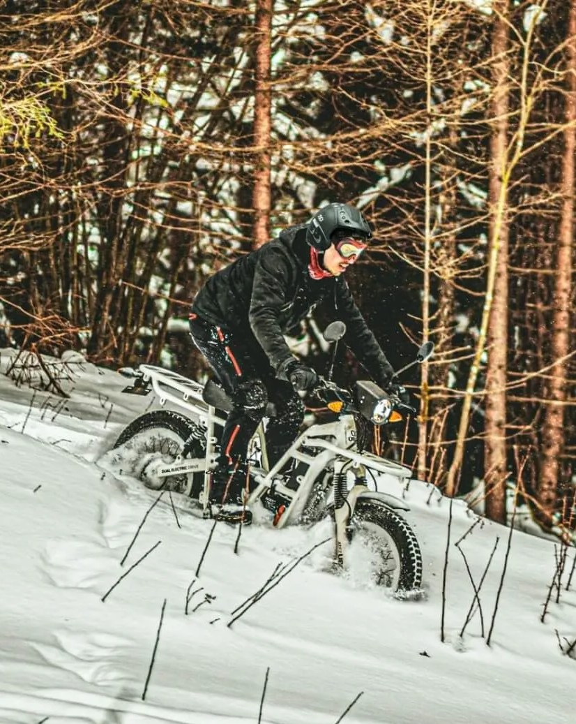 person riding ubco's new bike down snowy hillside