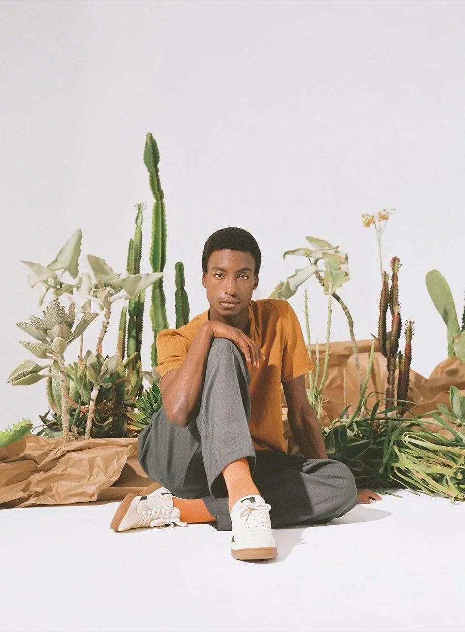 man sitting down wearing saye sneakers with cactus in the background