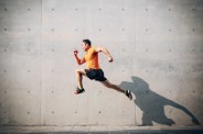sporty asian mid man running and jumping against shutter