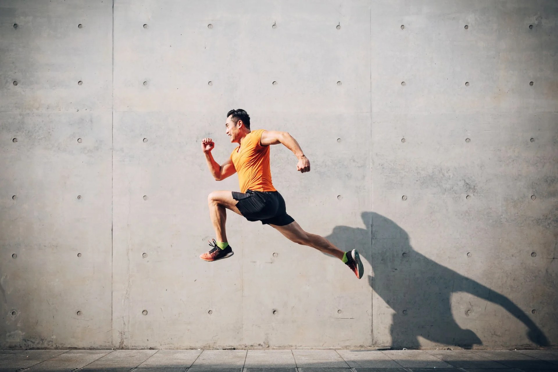 sporty asian mid man running and jumping against shutter
