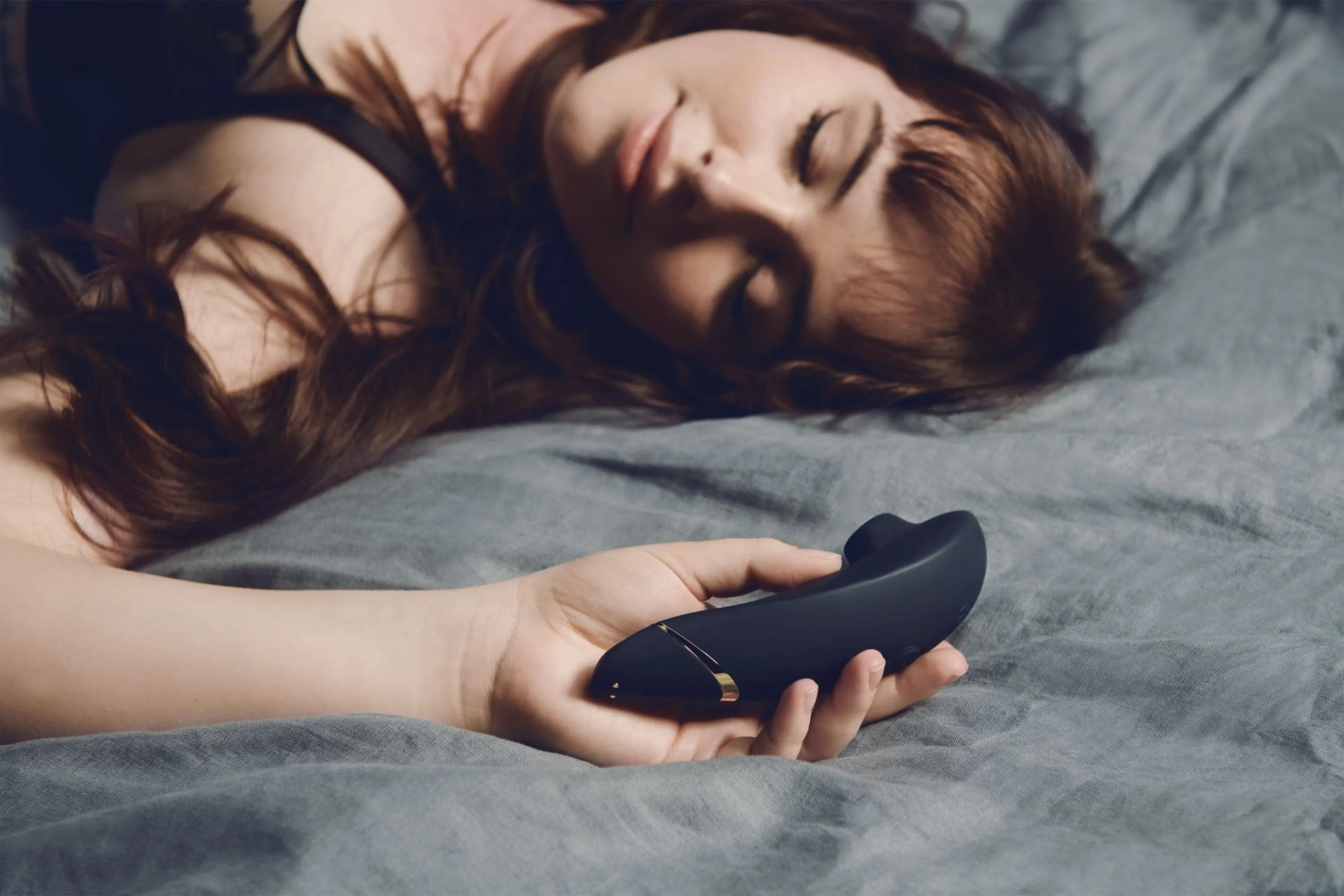 woman laying on bed with womanizer toy in hand