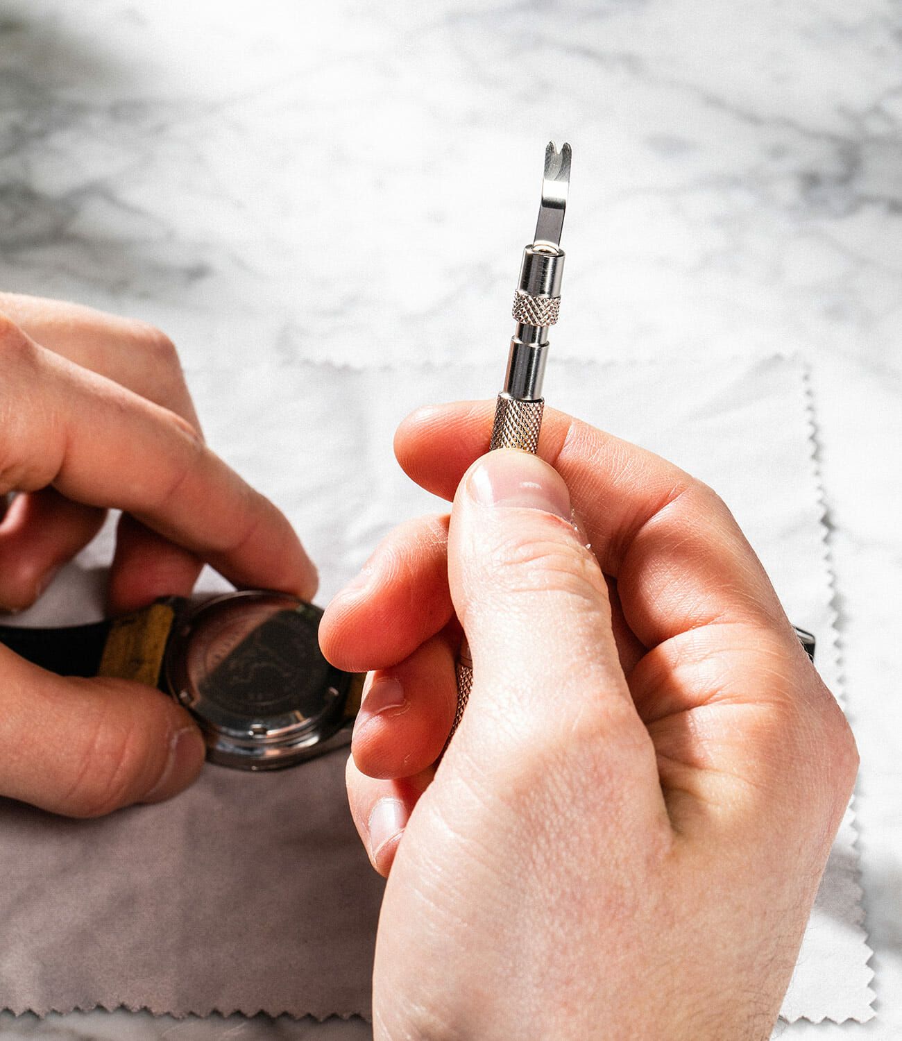 a man holds a spring bar tool while changing a watch strap