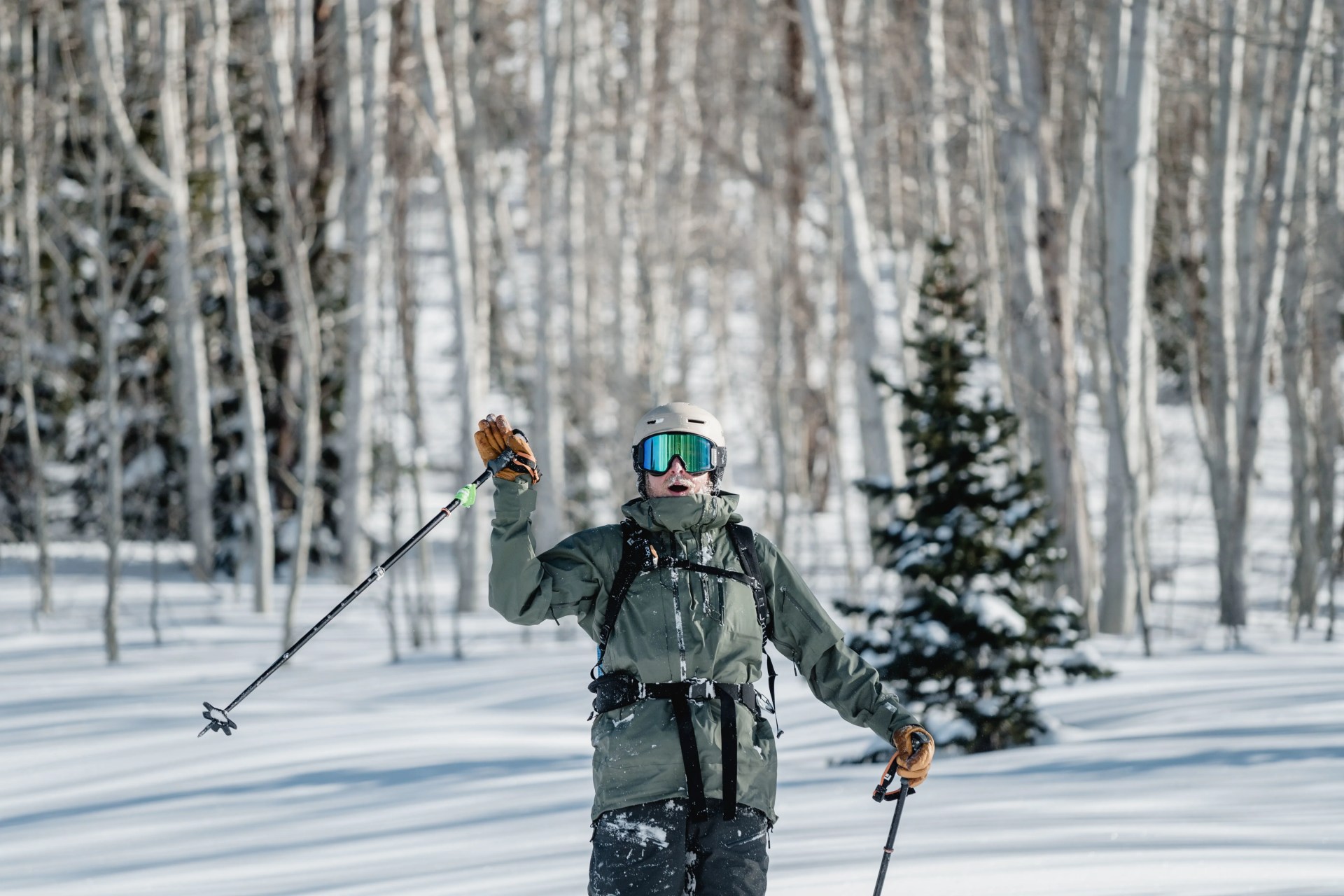 man waving while wearing ski gear in the snowy woods