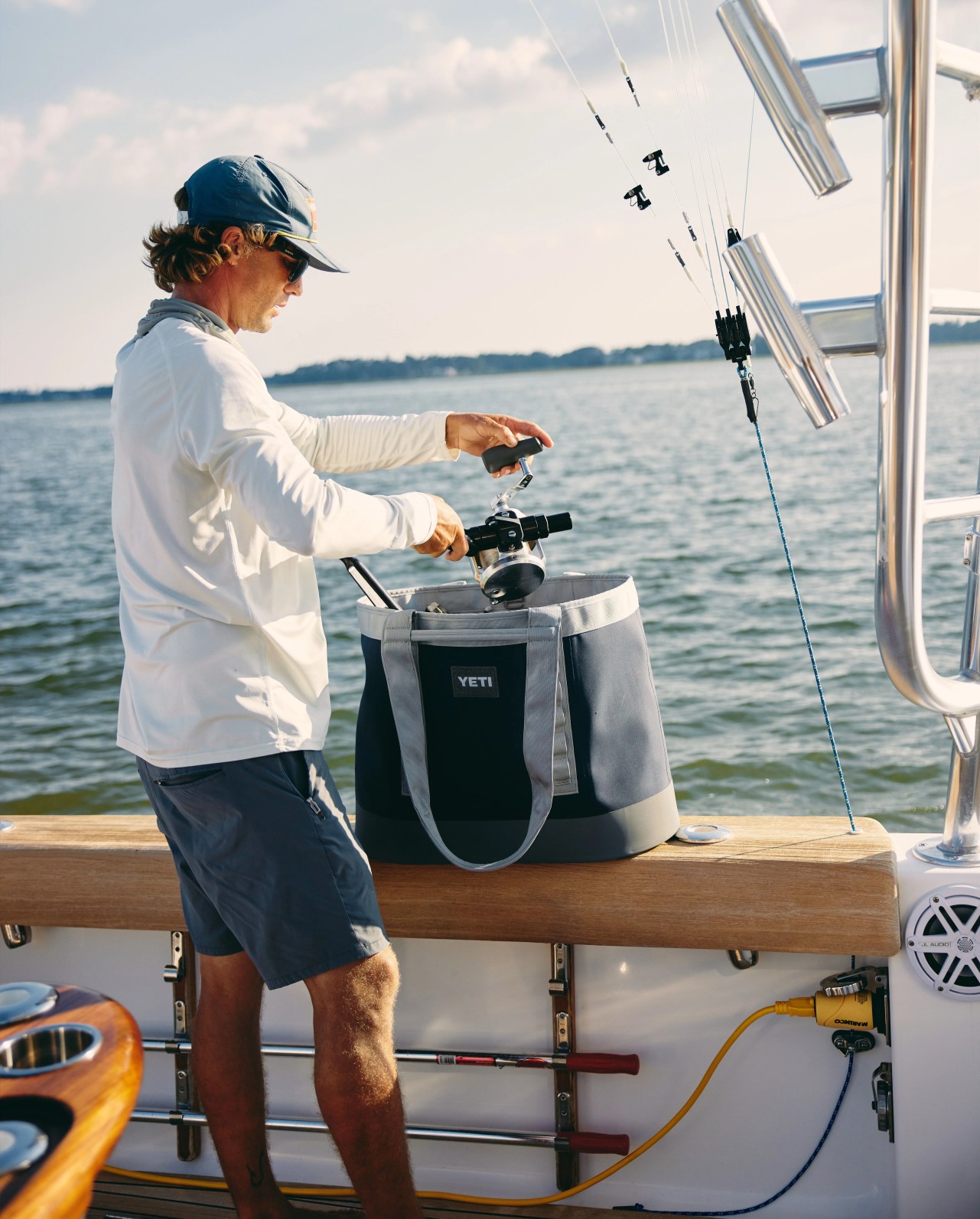 man putting things in camino 50 navy bag on side of boat