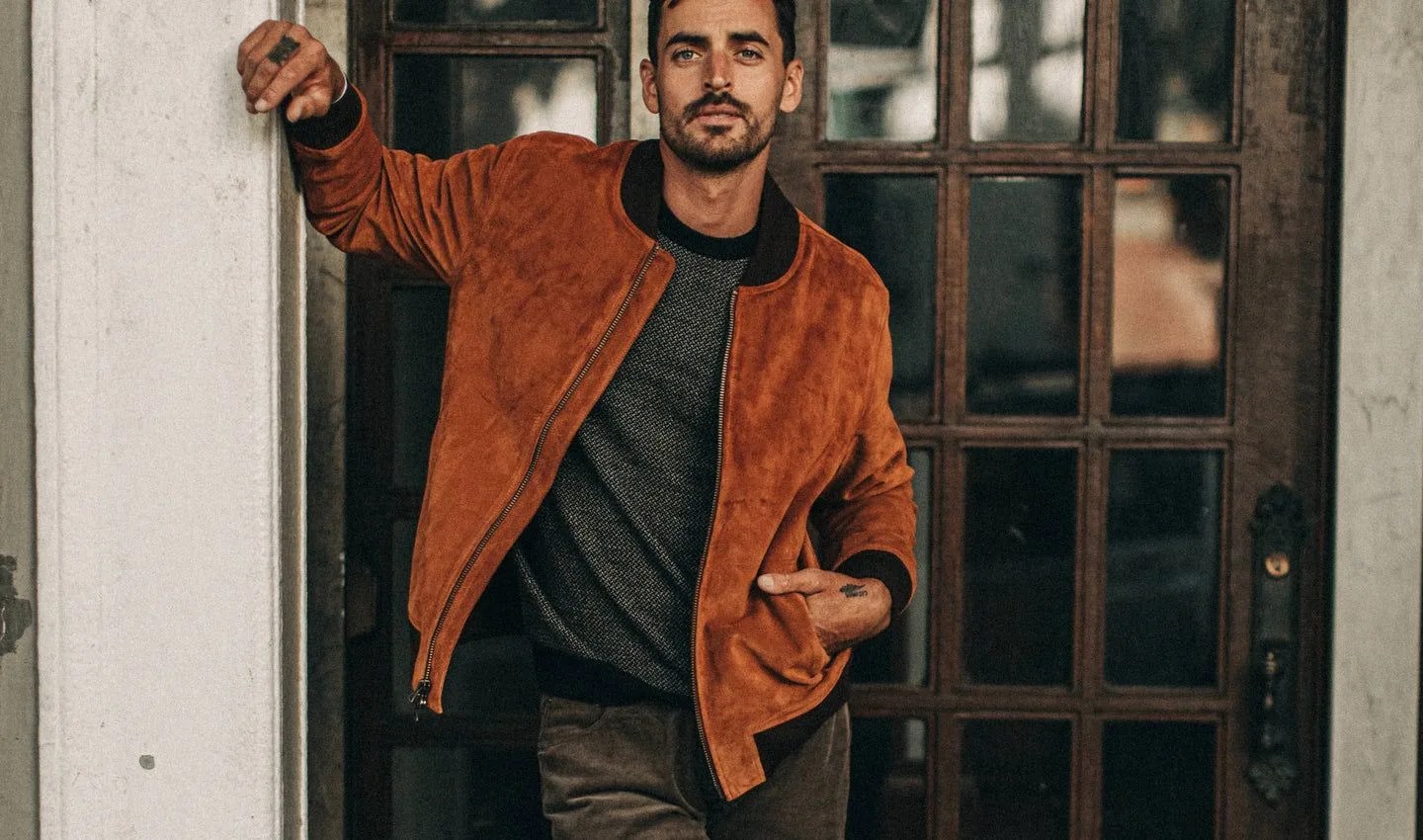man leaning against column wearing taylor stitch suede jacket