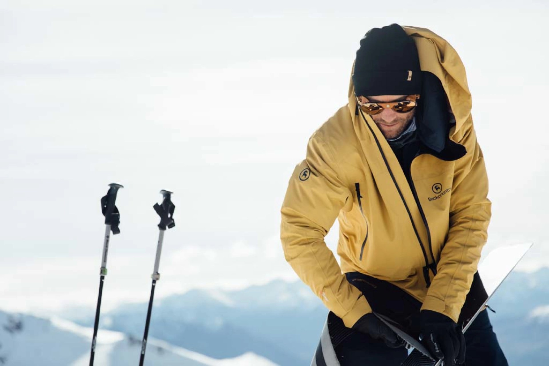 man standing on snowy mountain next to ski poles