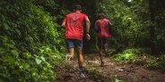 two men jogging through a woodsy trail wearing roark running gear