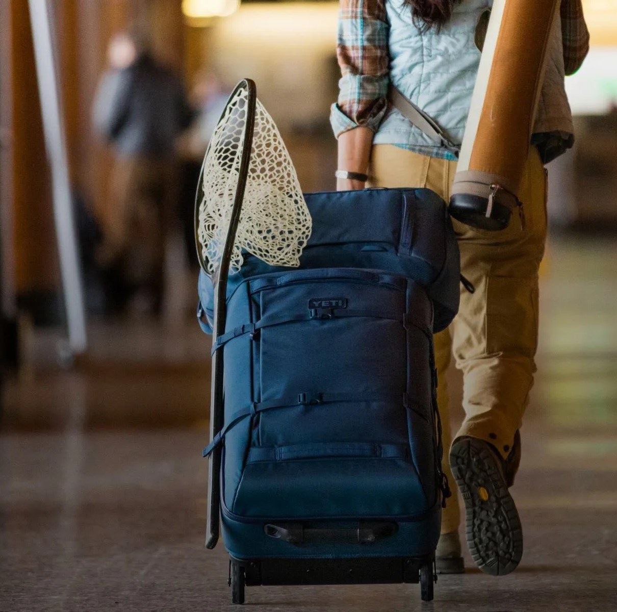 a person wheeling a yeti suitcase through an airport