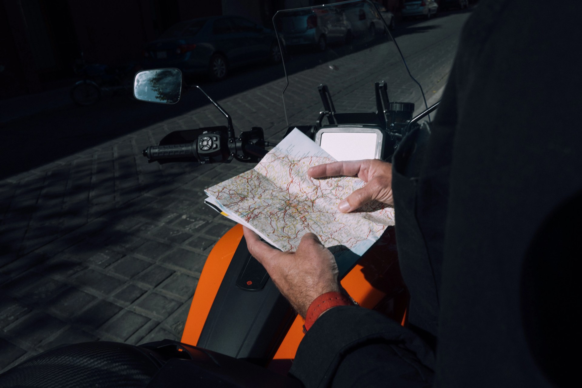 man holding a map next to motorcycle