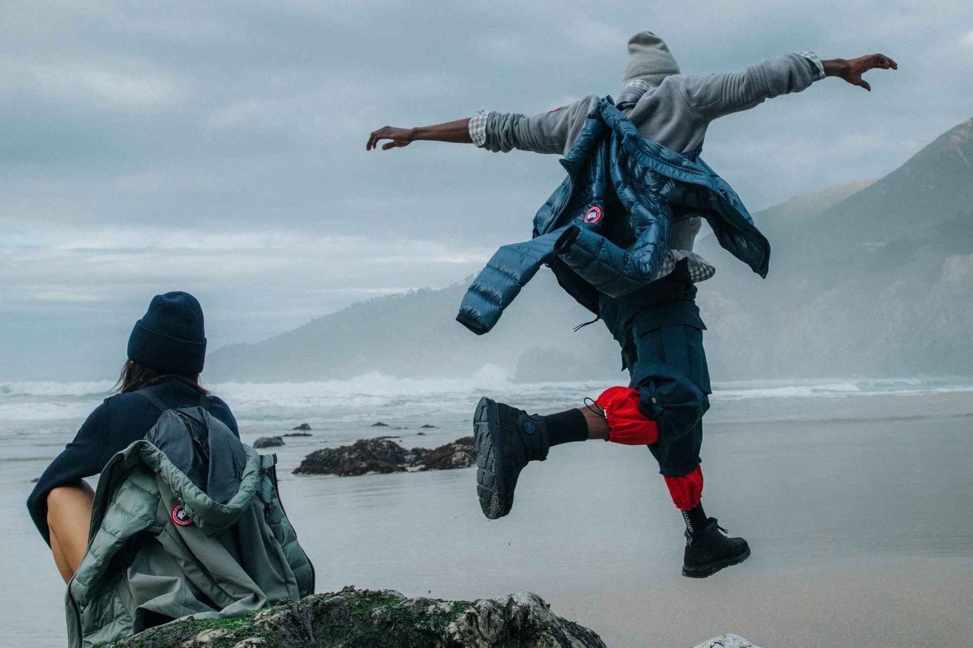 man and woman at the beach wearing canada goose clothing