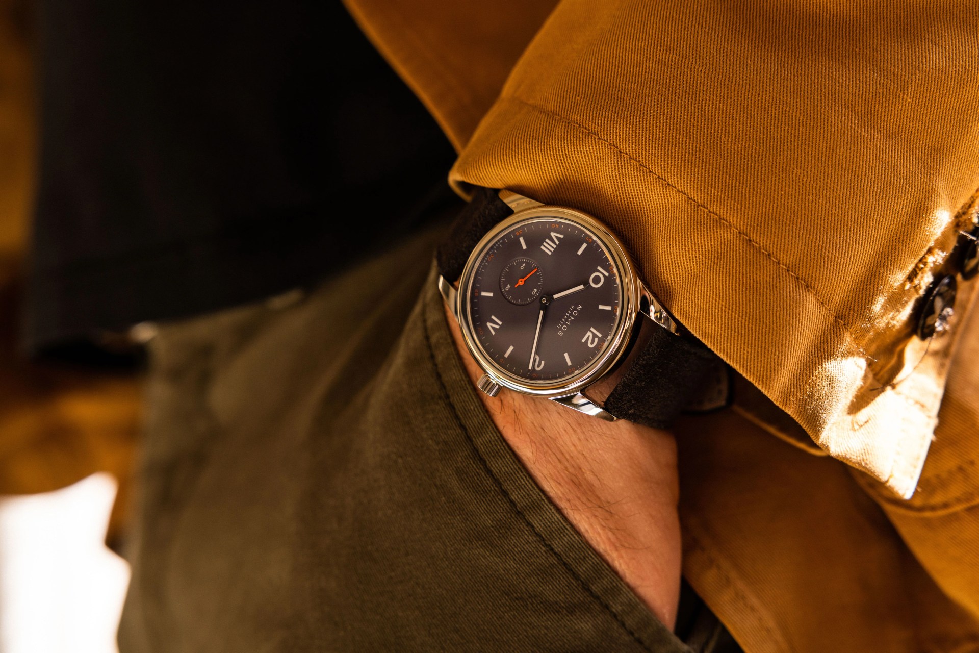 person with hand in pocket wearing nomos watch on wrist