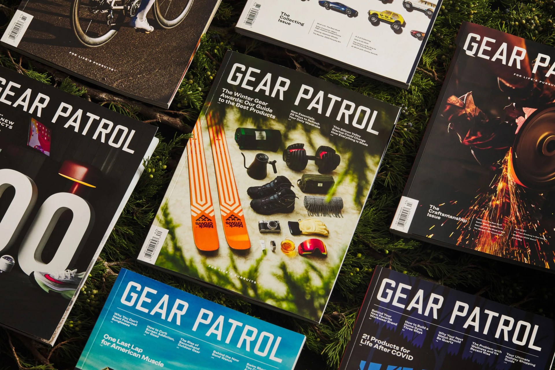 group shot of several editions of gear patrol magazine among tree branches