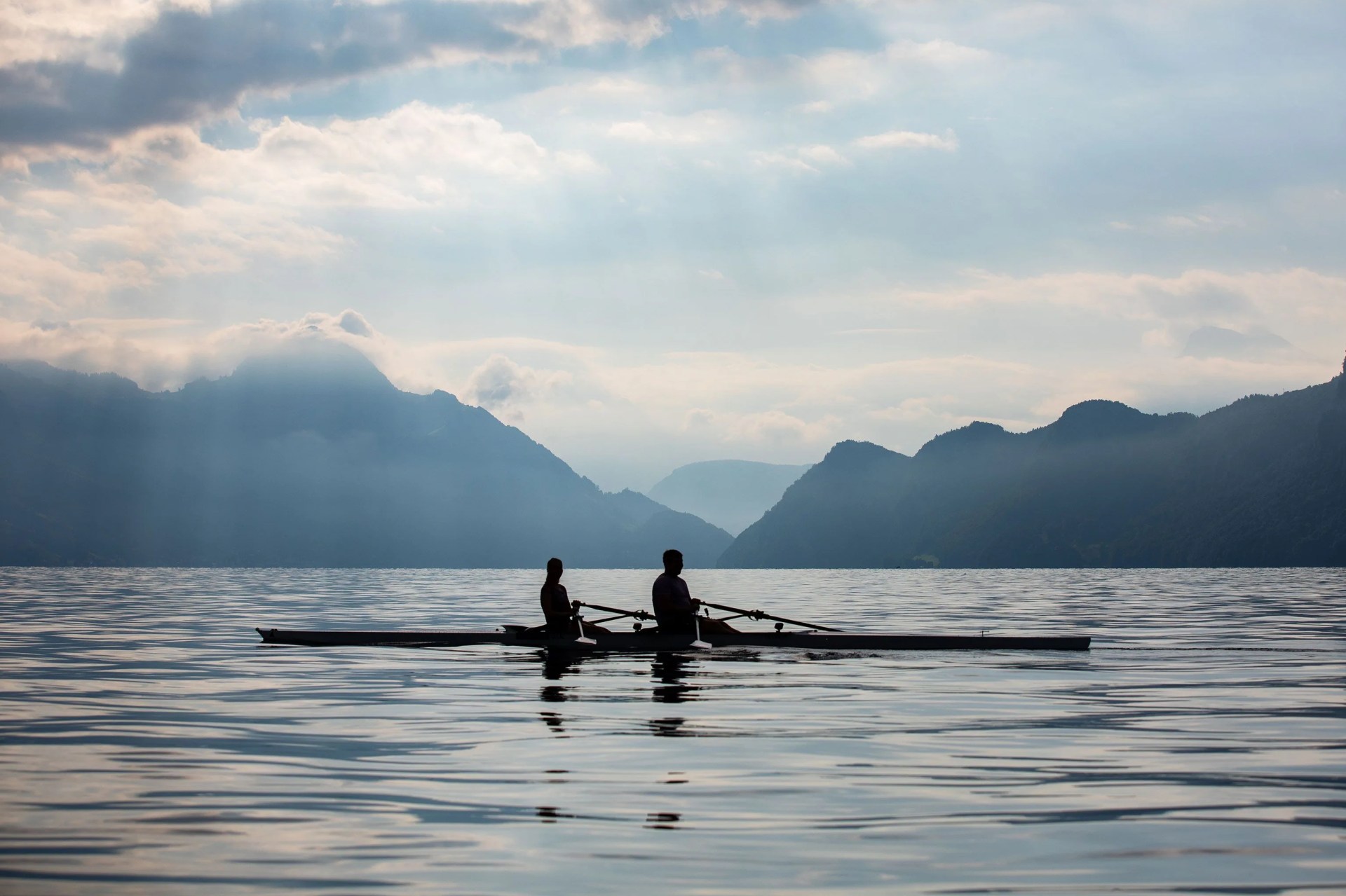 two people rowing on kayaks on a lake