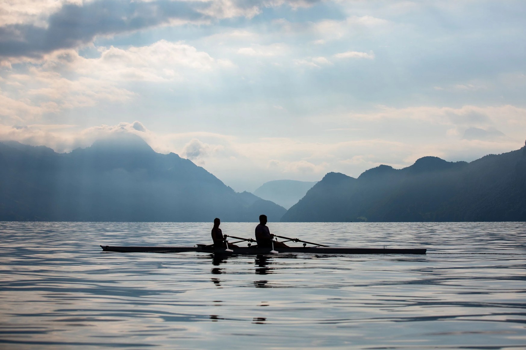 two people rowing on kayaks on a lake