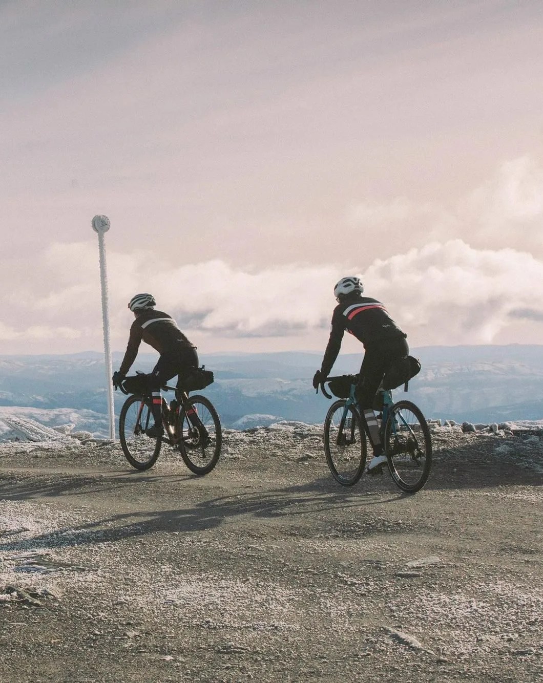 two people riding bikes wearing rapha brevit jacket