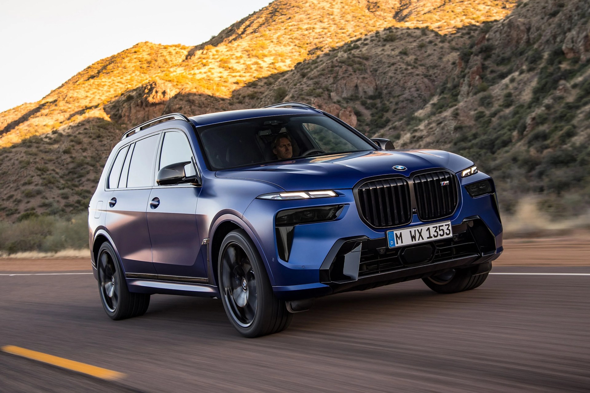 the new bmw x7 driving along a highway with mountains in the background