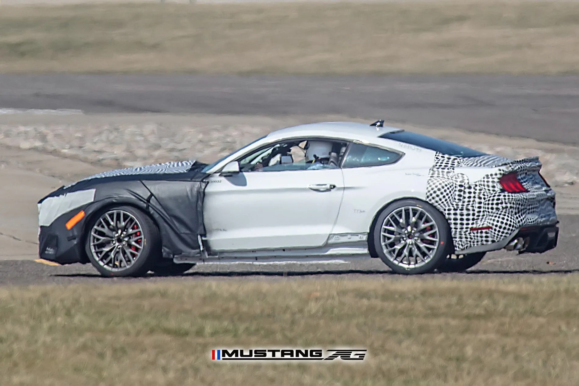spy shot of camouflaged ford mustang vehicle driving on a test track