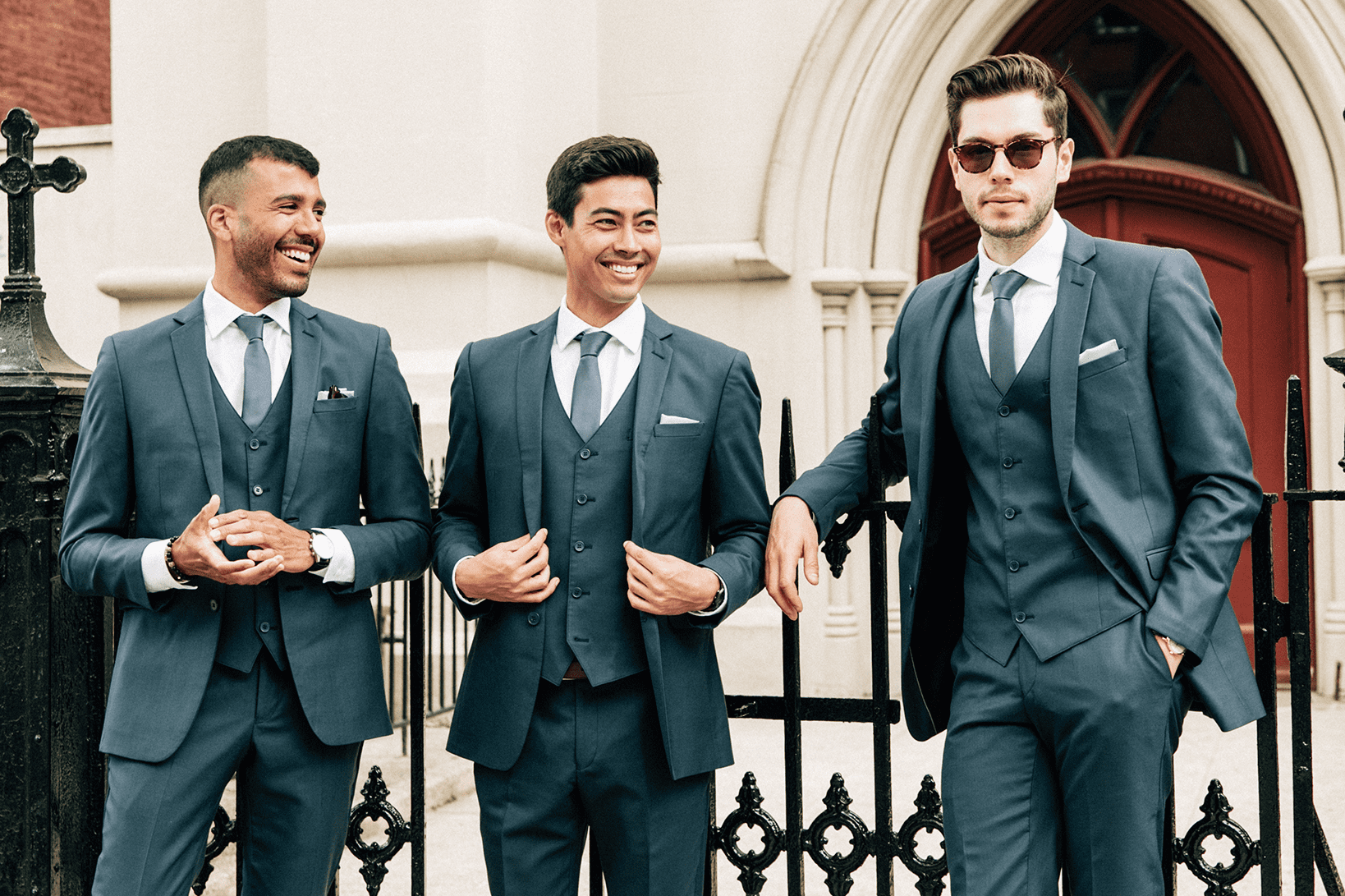three men leaning against gate wearing generation tuxes