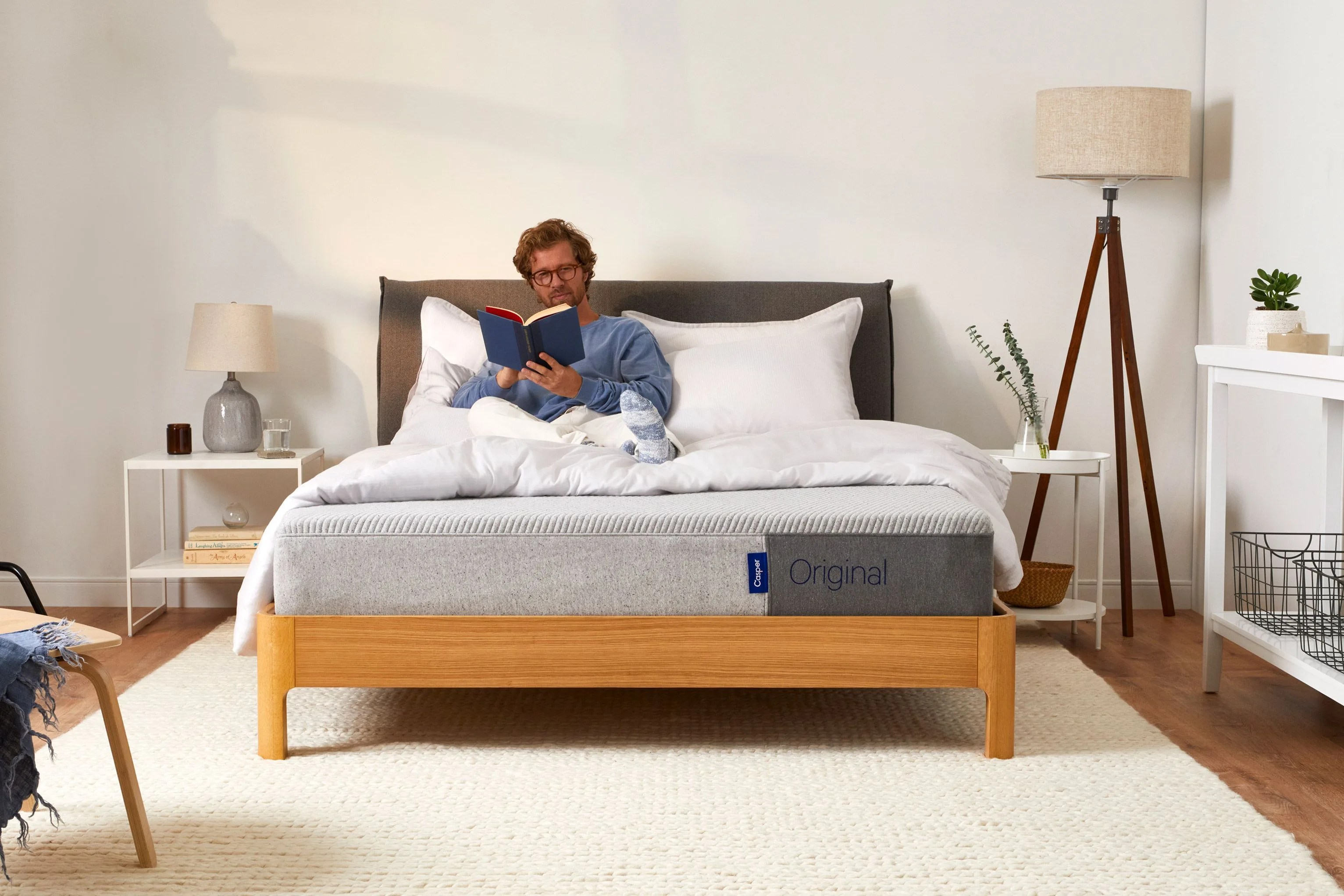 man reading a book sitting on top of casper original mattress