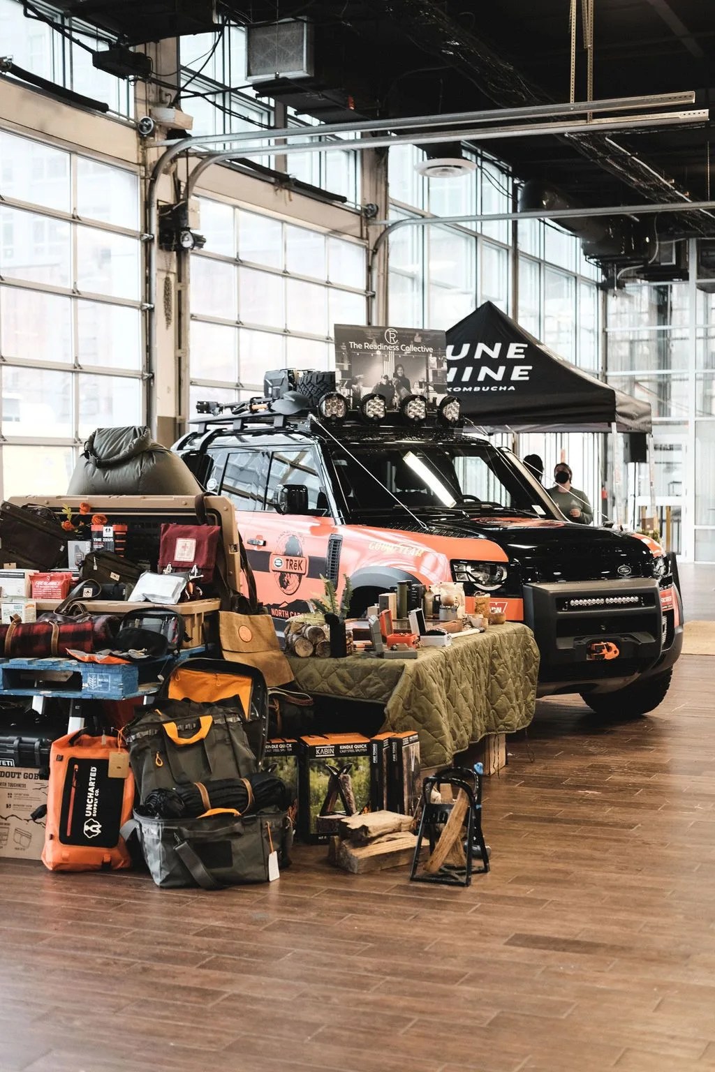 a pile of gear next to an orange car parked by a small booth inside a building