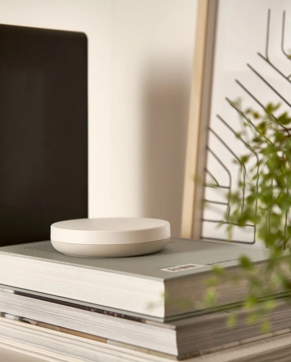 ikea's google matter ready hub dirigera sitting on top of books on a shelf