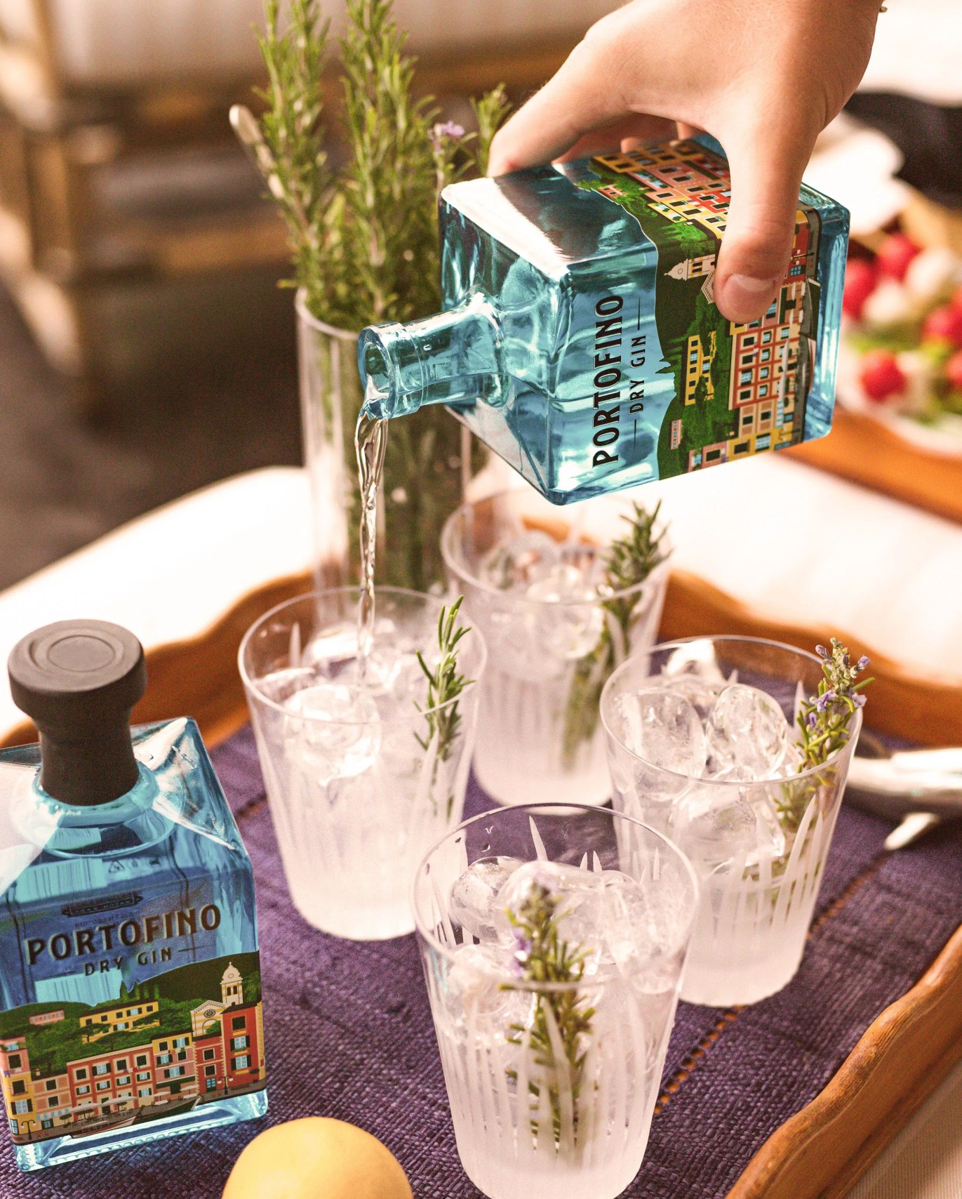 hand pouring portifino dry gin into glasses garnished with lavender