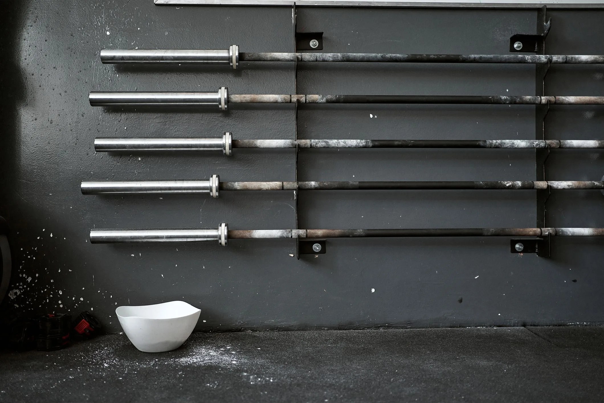 sports chalk bowl under a collection of barbells on a rack