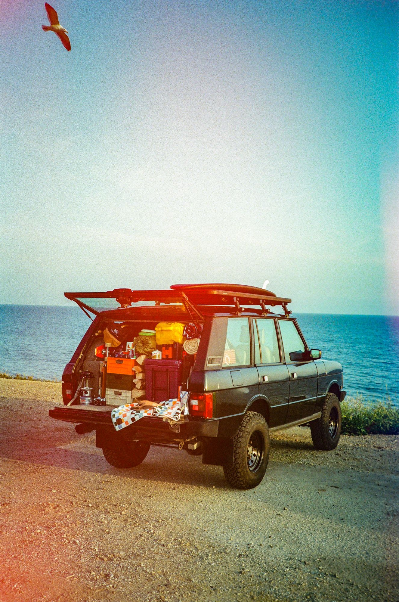 a vintage land rover packed with our favorite picks for a great summer