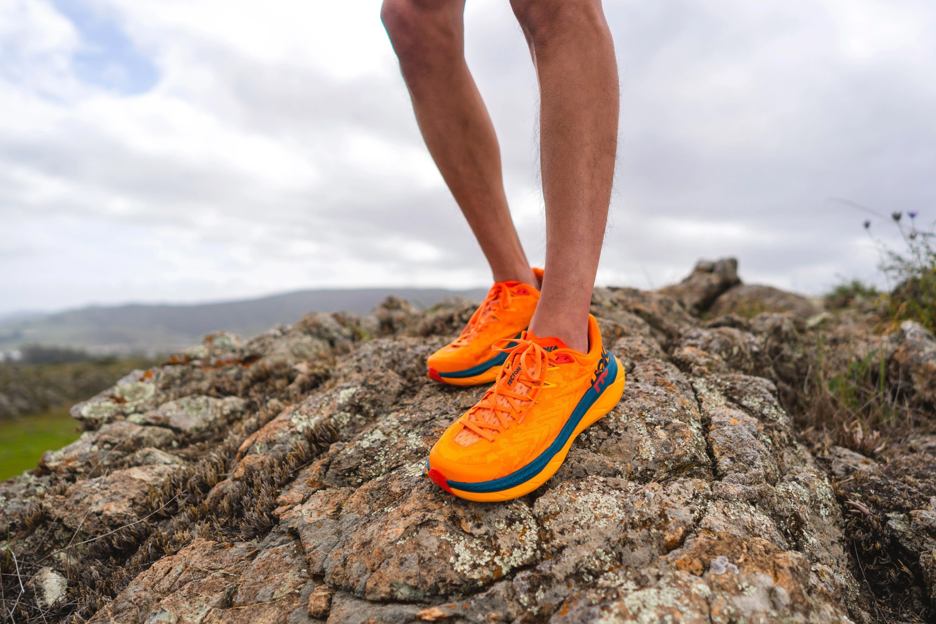 man standing on rock in hoka tecton x sneakers