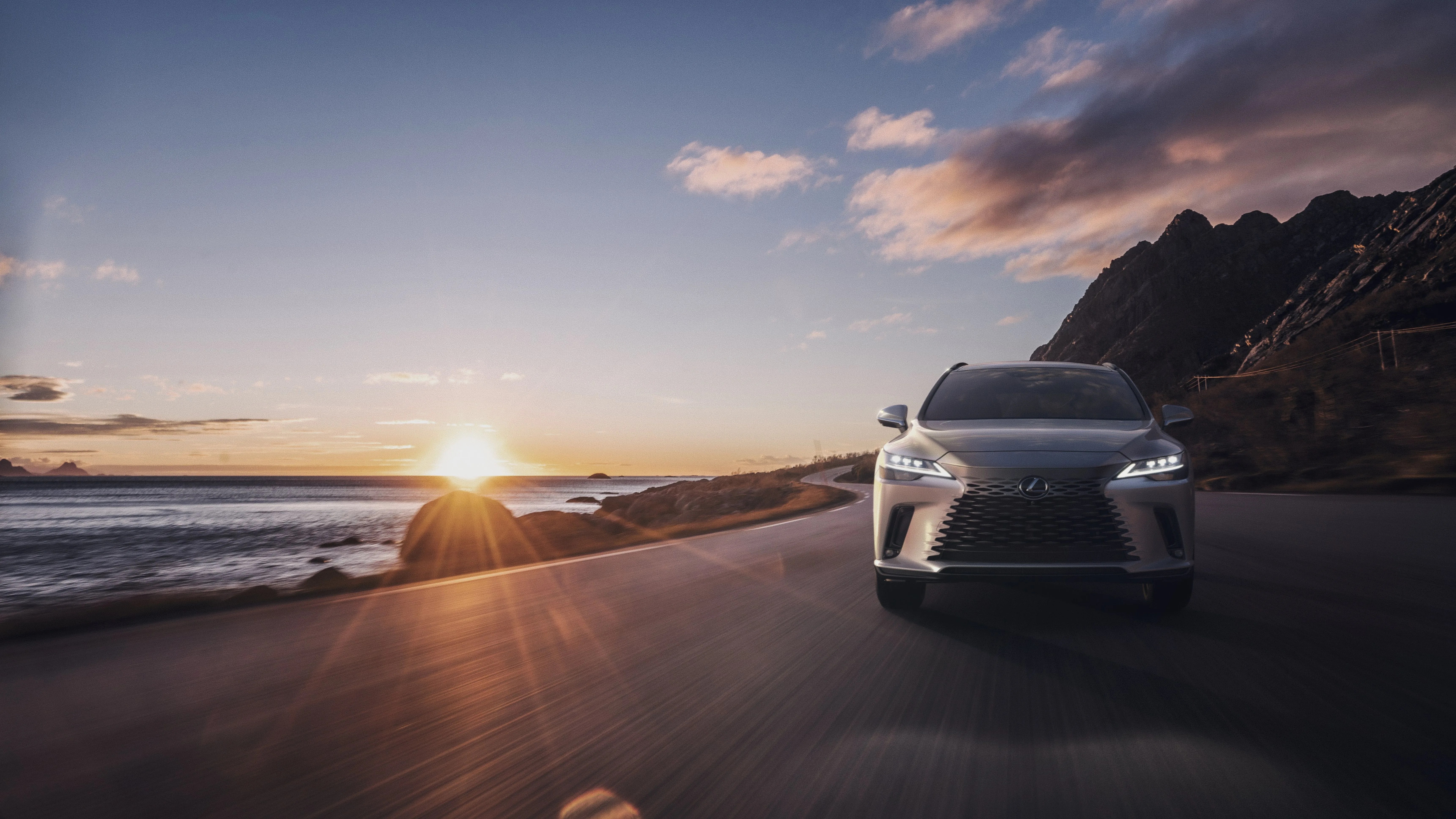 lexus rx driving on a coast road at sunset
