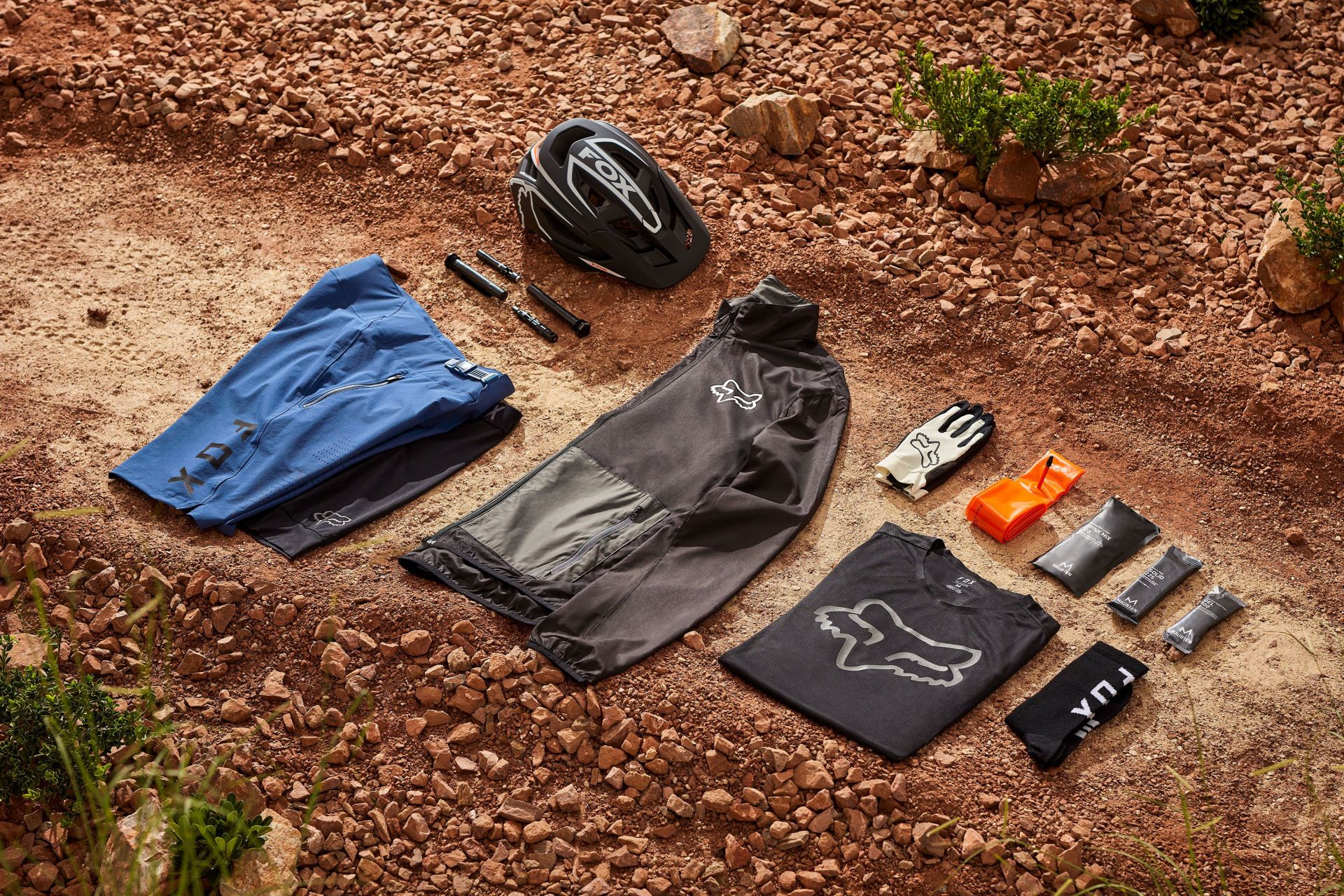 fox racing mountain bike ride kit with helmet, shorts, jacket, gloves, socks, shirt laying in red rock and dirt