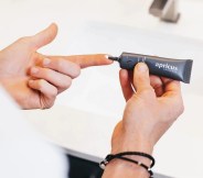 person using a tube of apricus skincare tinted moisturizer