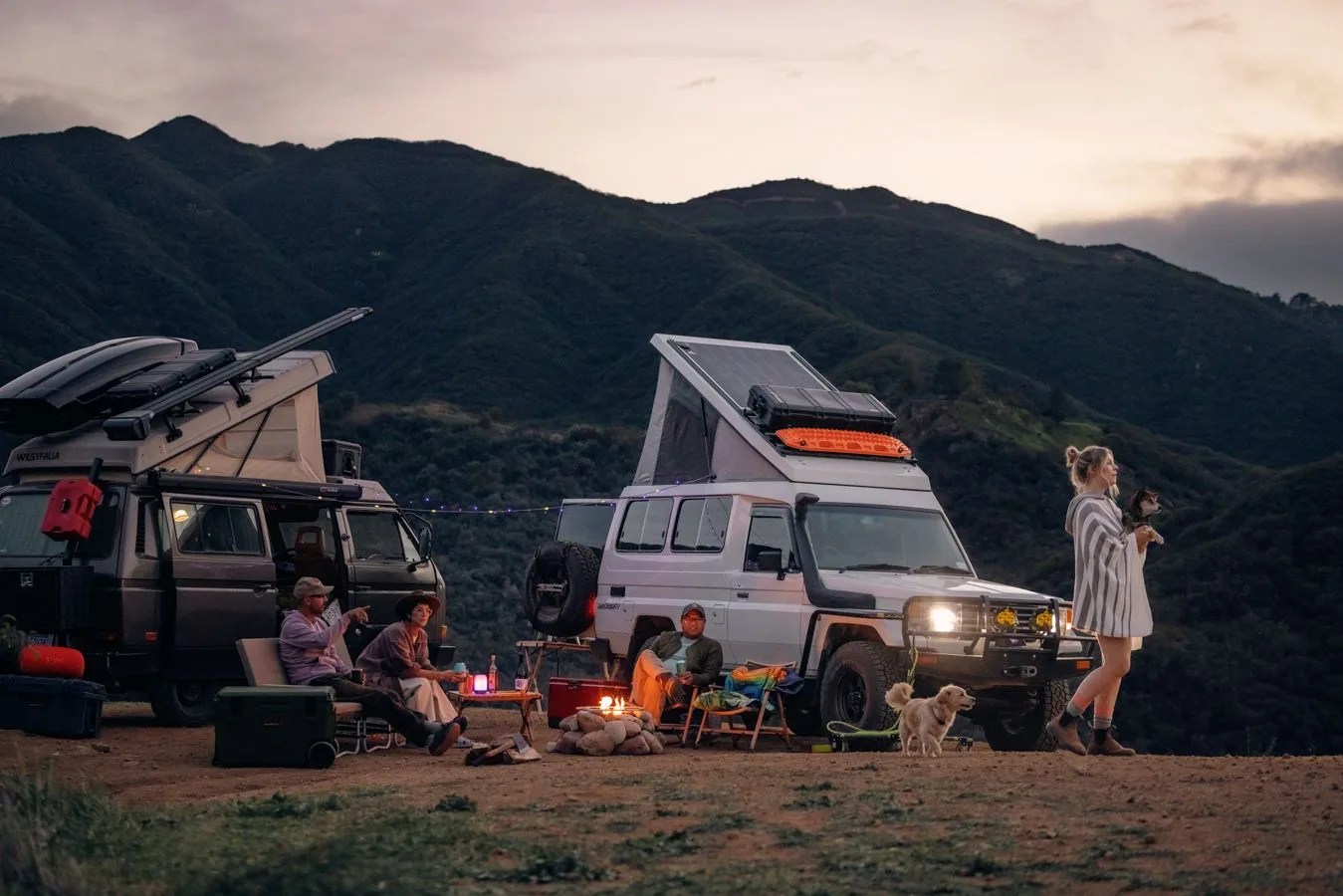 people sitting around a campfire next to their rv in the mountains with backcountry gear