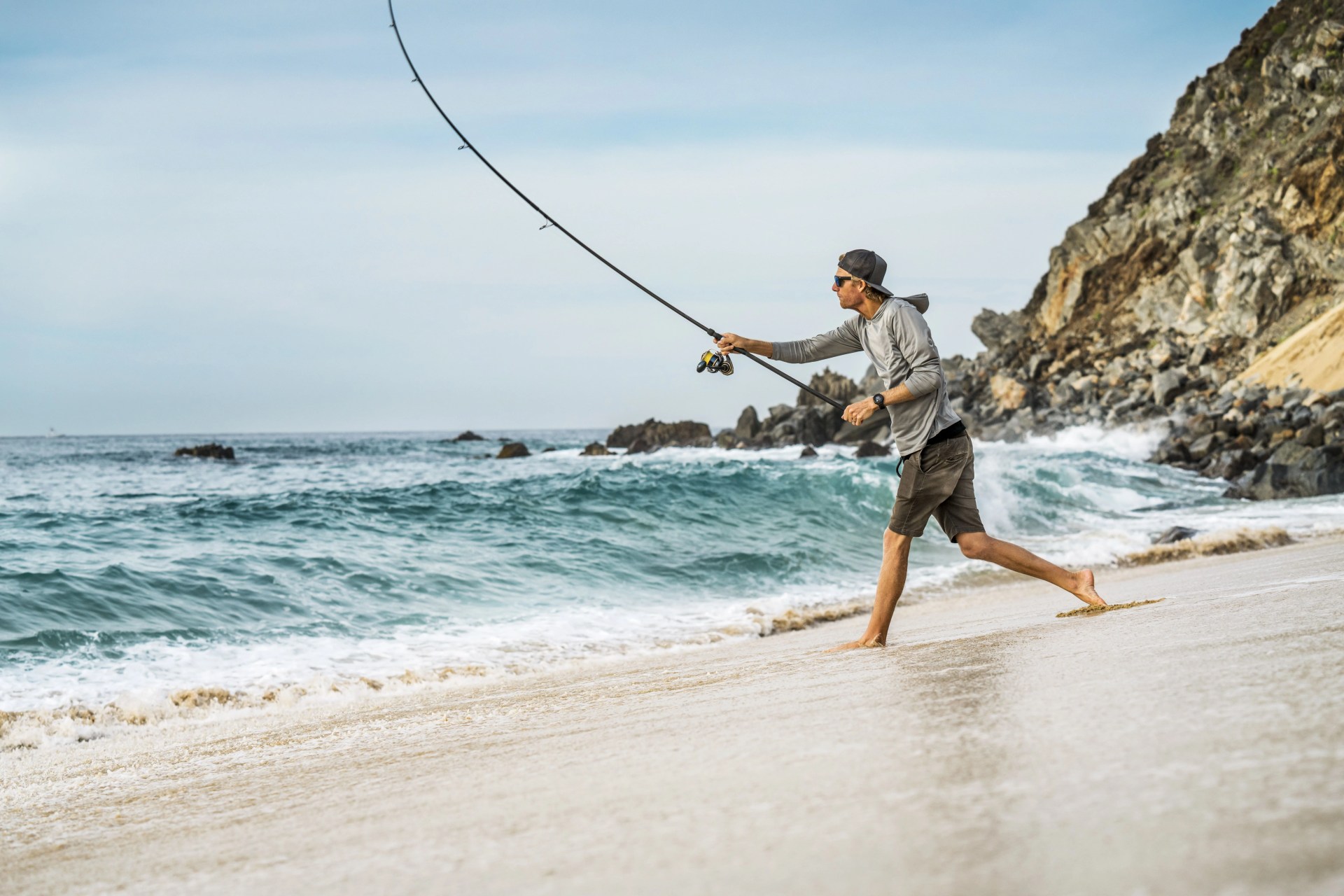 man wearing costa sunglasses while fishing at the beach