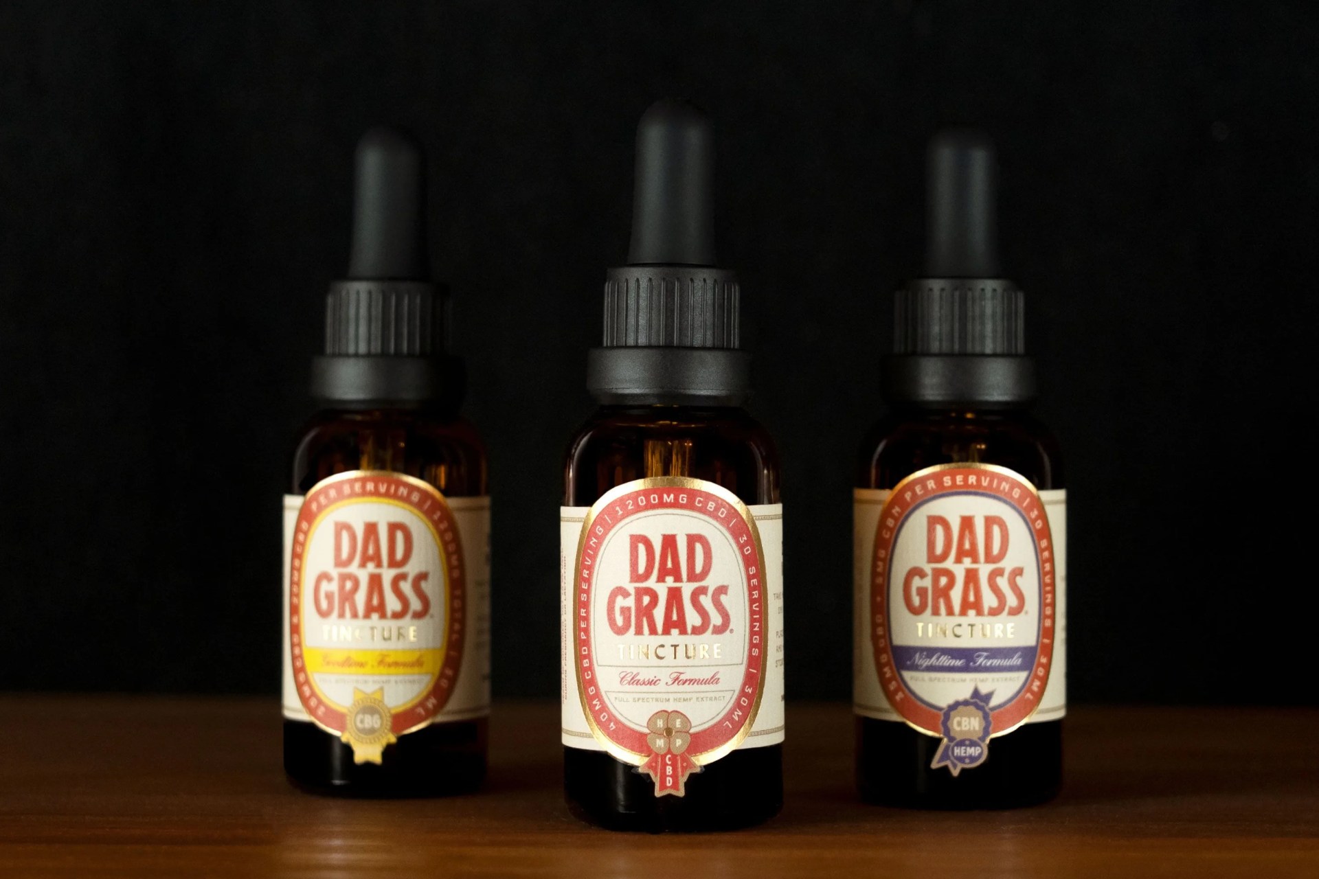 three dad grass tinctures lined up next to each other on wooden surface