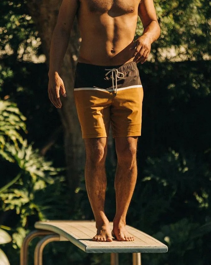 man wearing taylor stitch turning the tide capsule swim trunks standing on a diving board